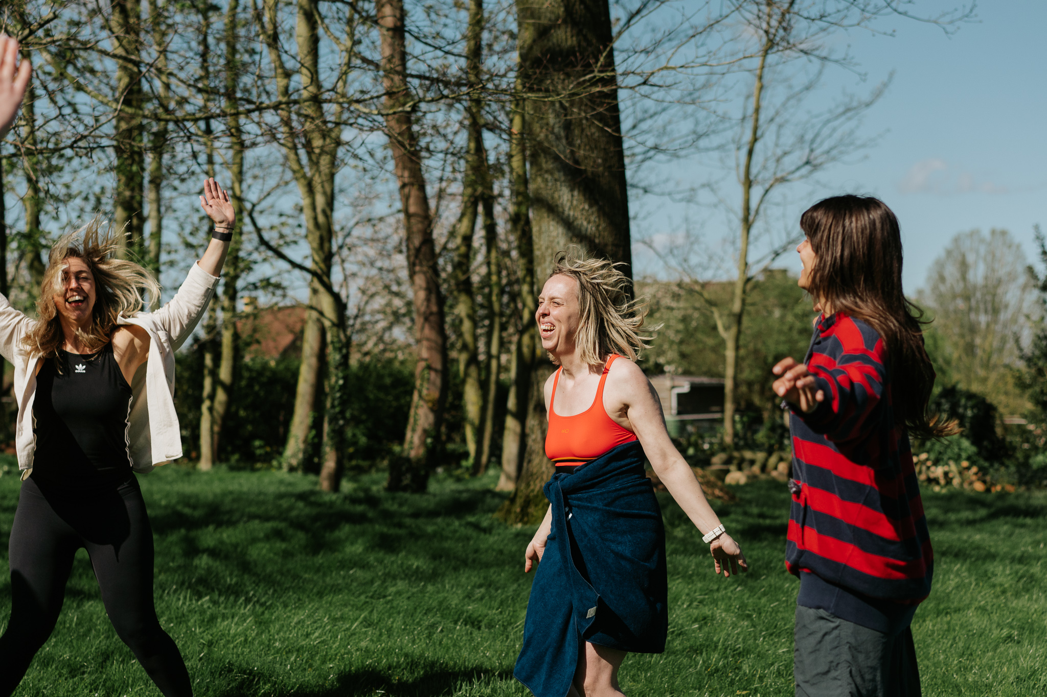 Drie vriendinnen lachen en dansen op het gras na hun ijsbad